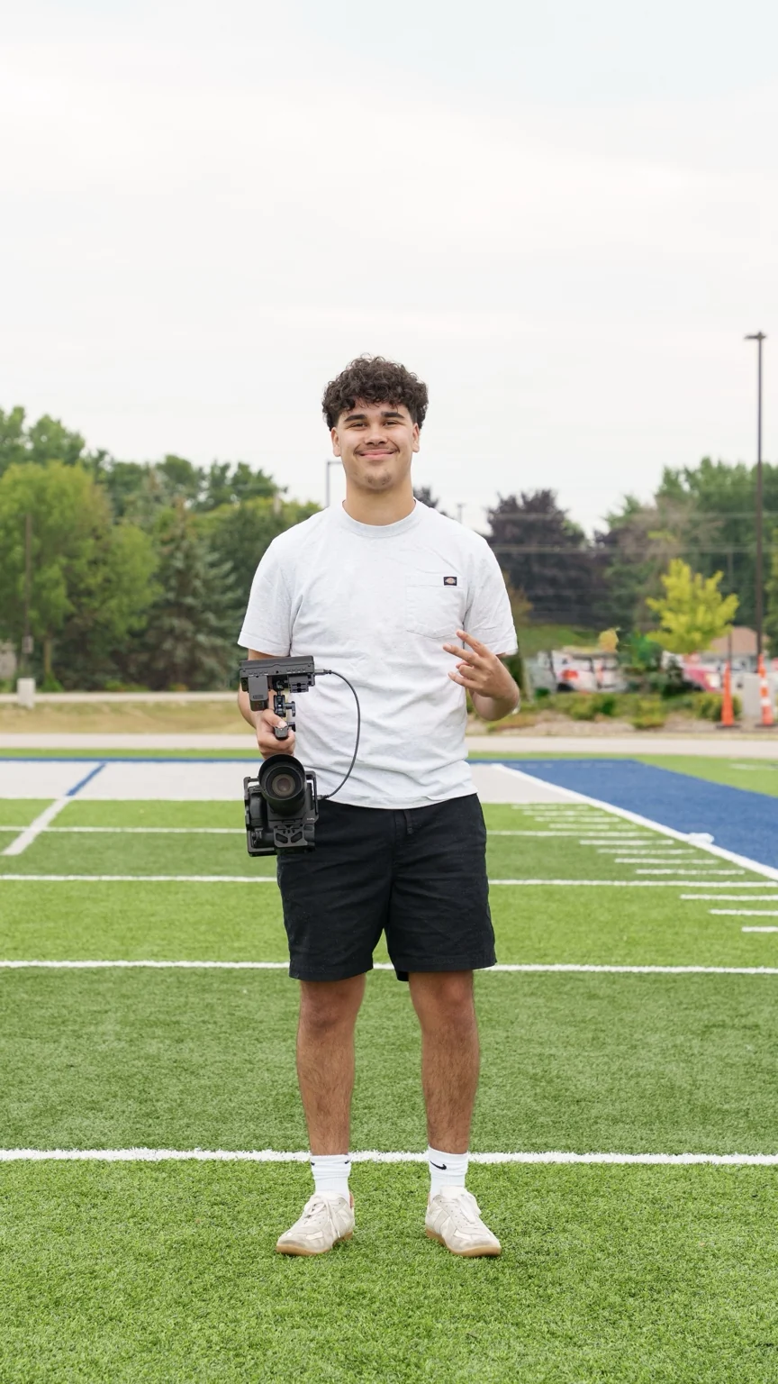 Carter Folts holding a camera on a football field